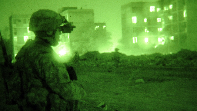 Photo of a solider viewed through the green filter of night vision goggles. 