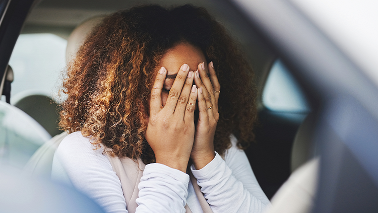 Photograph of woman looking distressed in her car