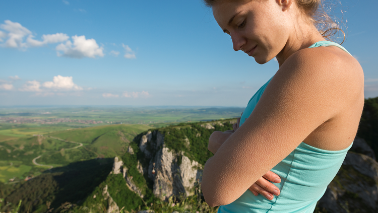 woman with goosebumps looking out on a cliff 