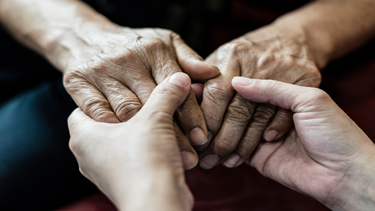 Young hands holding older person's hands