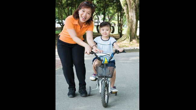 A woman helps her daughter ride a bike