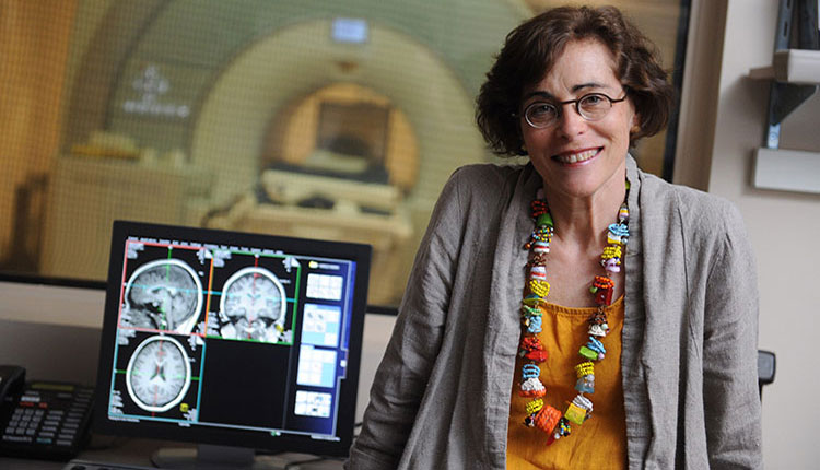 photo of marlene Behrmann next to computer with images of brains