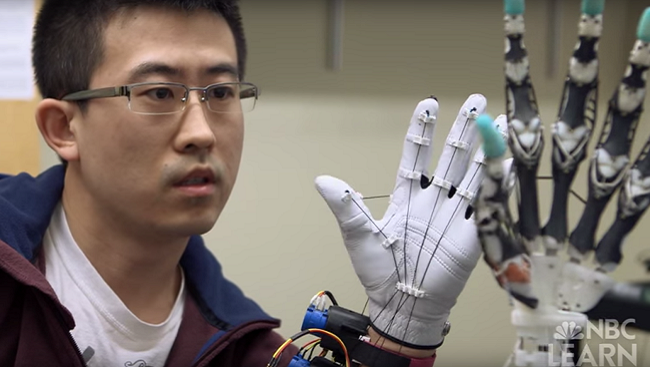 Man holds his hand next to a robotic prosthetic hand. 