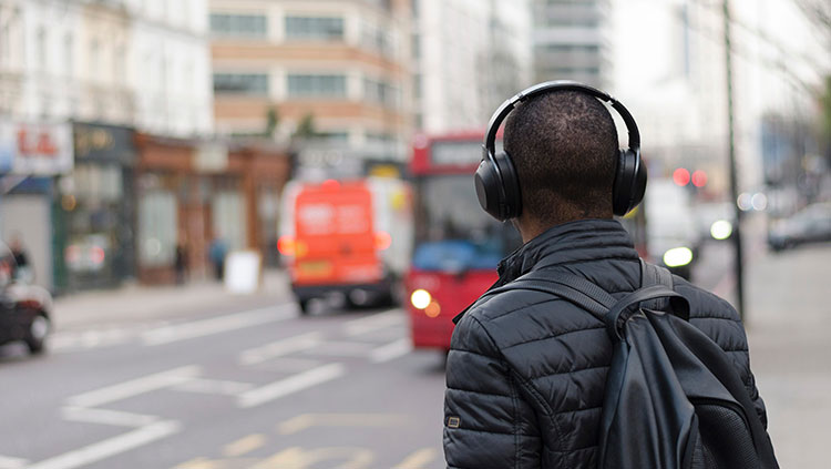 man in the city with his back turned wearing headphones