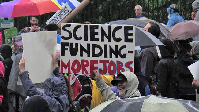 Marcher holds sign that reads: "Science Funding = More Jobs"