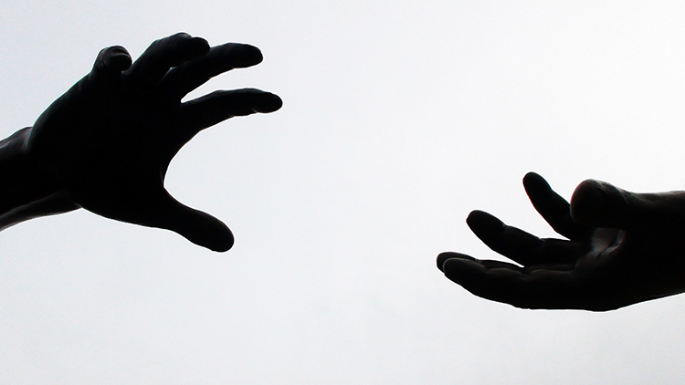 Hands separated reach out toward each other for help.