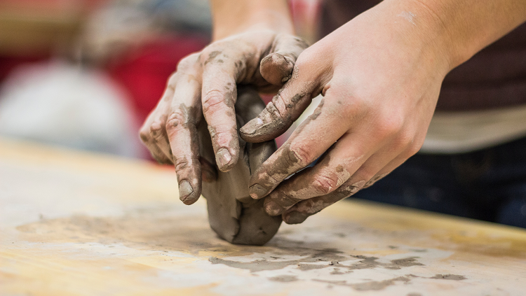 hands molding brown clay