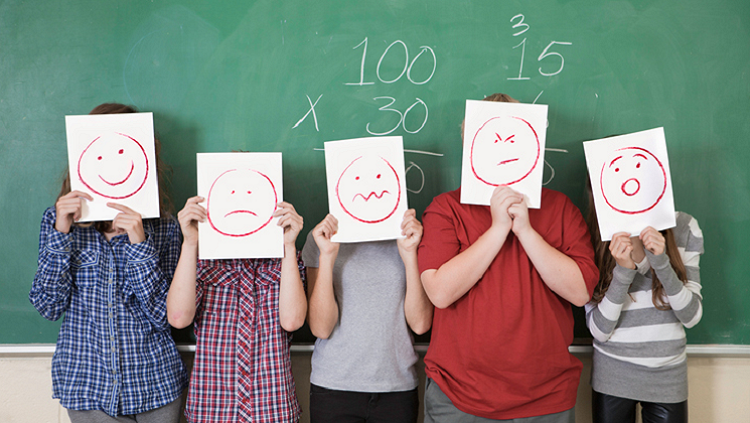 Image of children with drawn faces on paper in front of their faces