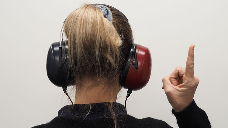 Woman with headphones holding index finger into the air