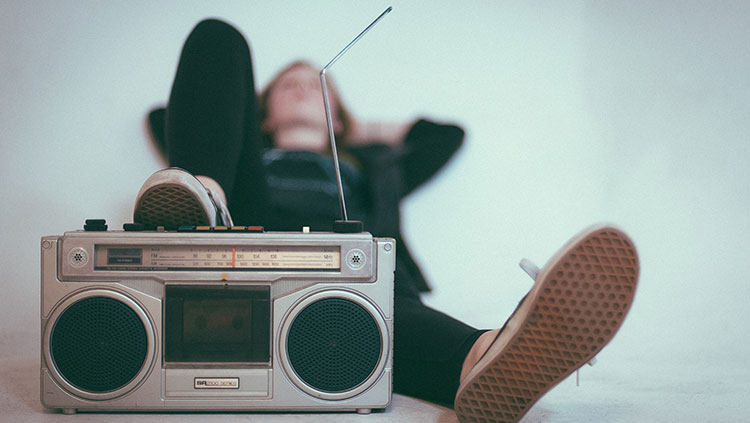 Young woman listening to a boom box while lying down